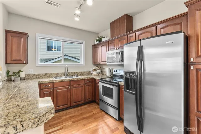 a kitchen with stainless steel appliances granite countertop a sink stove and refrigerator