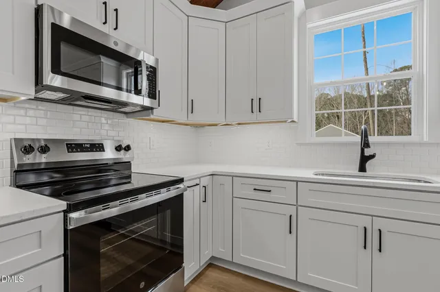 a kitchen with white cabinets stainless steel appliances and a sink