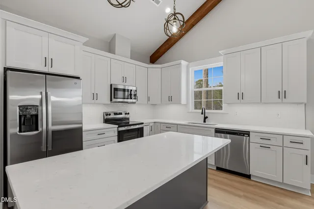 a kitchen with stainless steel appliances granite countertop a sink a stove a refrigerator cabinets and chairs