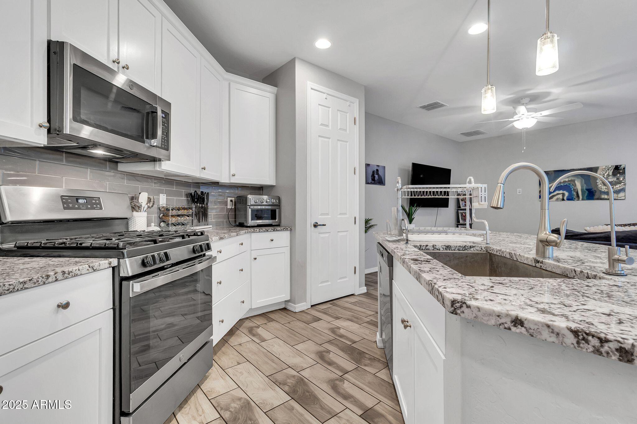4145 East Bethena Street Gilbert, AZ 85295 - Photo 13 of 60 a kitchen with stainless steel appliances granite countertop a stove top oven a sink dishwasher a refrigerator and a microwave