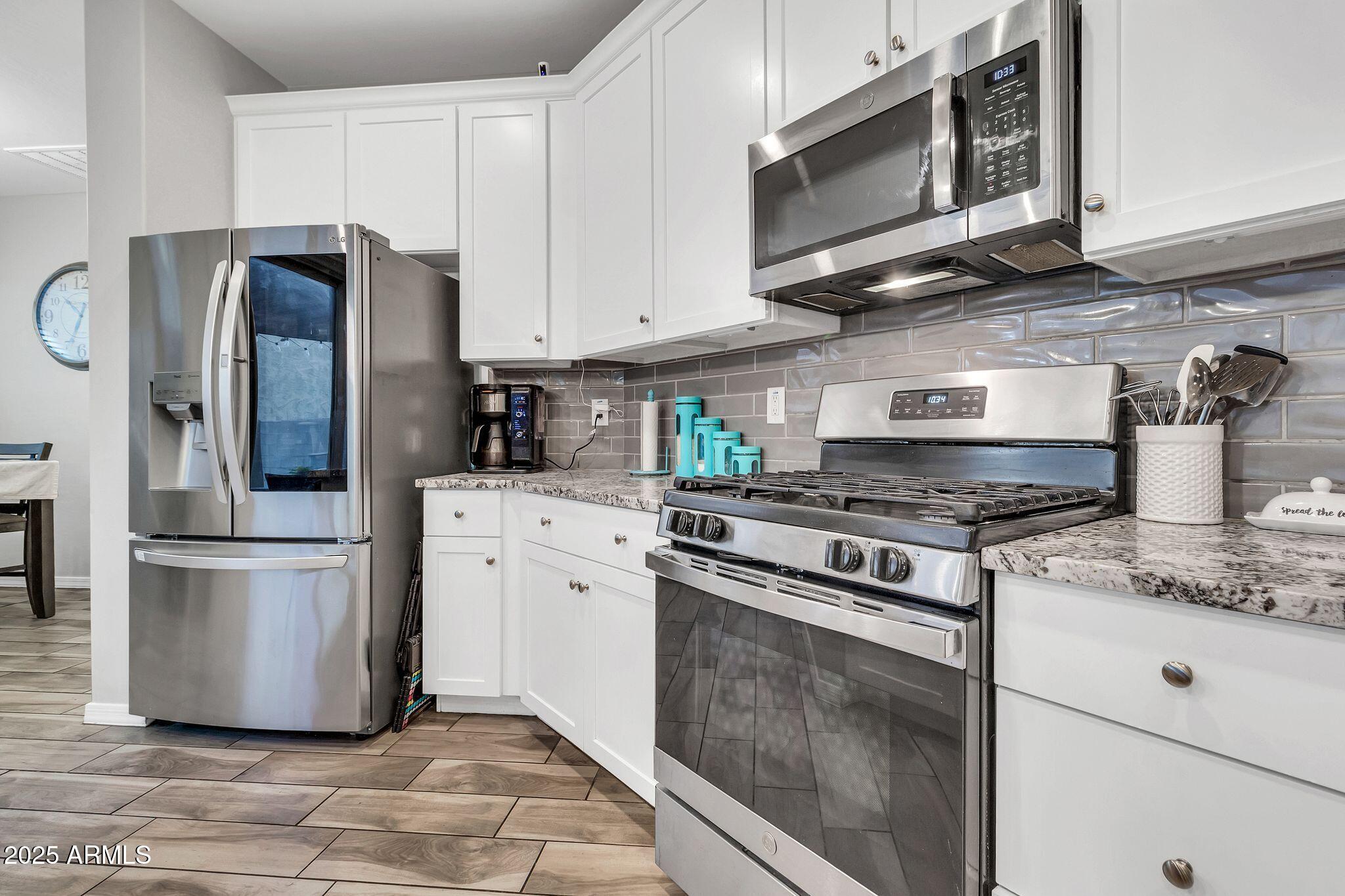 4145 East Bethena Street Gilbert, AZ 85295 - Photo 14 of 60 a kitchen with stainless steel appliances granite countertop a stove a refrigerator and a microwave