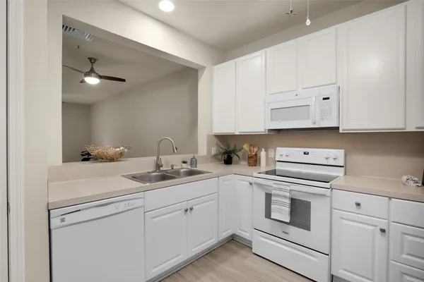an empty room with a chandelier fan and windows