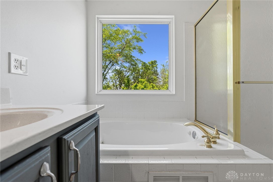 70 Martin Lane Springboro, OH 45066 - Photo 41 of 69 This bathroom features a deep soaking tub and a bright window overlooking lush greenery.