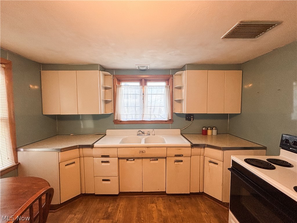 724 East Main Street Barnesville, OH 43713 - Photo 8 of 28 Kitchen with electric range oven, dark wood-style flooring, light countertops, and cream cabinets