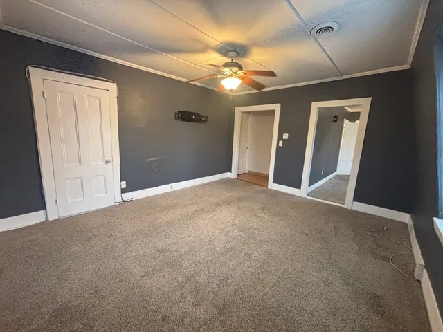 a view of an empty room with a chandelier fan