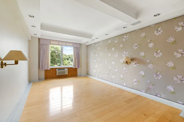 a view of an empty room with a window and a kitchen