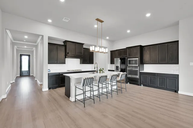 a kitchen with stainless steel appliances kitchen island granite countertop a table chairs microwave and sink