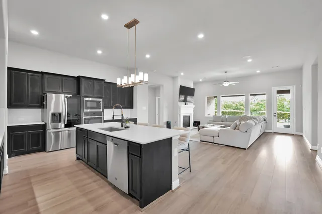 a large kitchen with stainless steel appliances kitchen island a large counter top a sink a stove and a center island