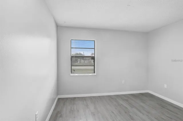 a view of an empty room and wooden floor and a window