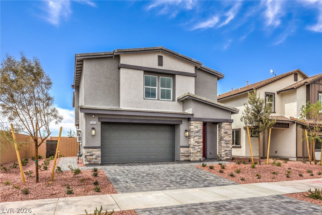 1017 Copper Robin Street Henderson, NV 89011 - Photo 3 of 43 Photo is representational only; actual home finishes may vary. Traditional-style home with an attached garage, stone siding, decorative driveway, and stucco siding