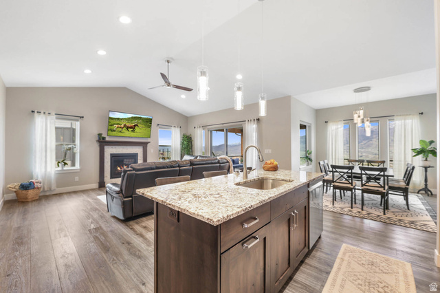 4527 North Seven Bridges Road Eden, UT 84310 - Photo 63 of 65 Kitchen with dark wood finish cabinetry, an island with sink, open floor plan, light stone countertops, and light wood-style floors