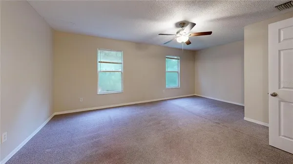 an empty room with windows and chandelier fan