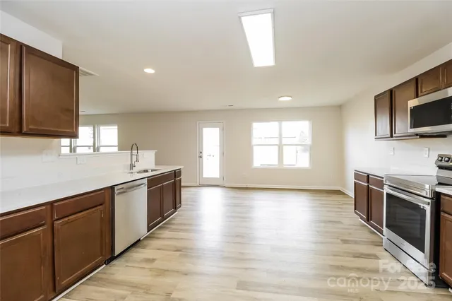 a large kitchen with wooden floors and stainless steel appliances