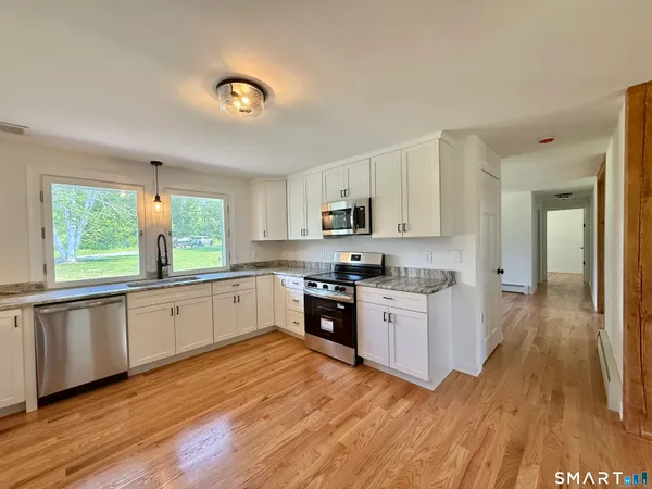 a large kitchen with a wooden floor and stainless steel appliances