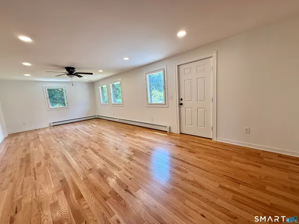 a view of empty room with wooden floor and fan