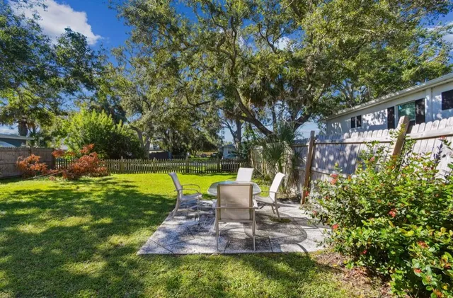 a view of a patio with table and chairs potted plants and large tree