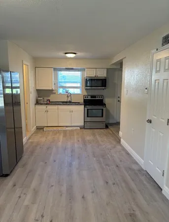 a kitchen with stainless steel appliances a refrigerator and wooden floor