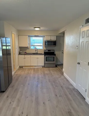 a kitchen with stainless steel appliances a refrigerator and wooden floor