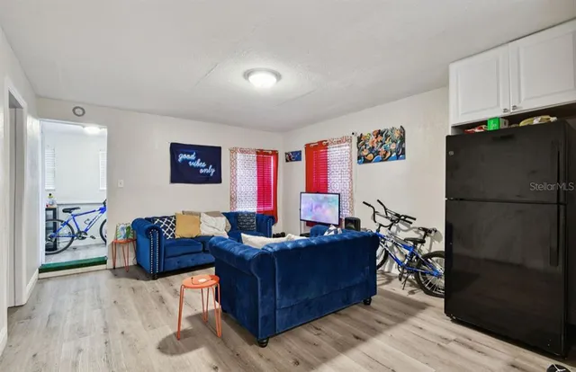 a living room with furniture a wooden floor and a refrigerator