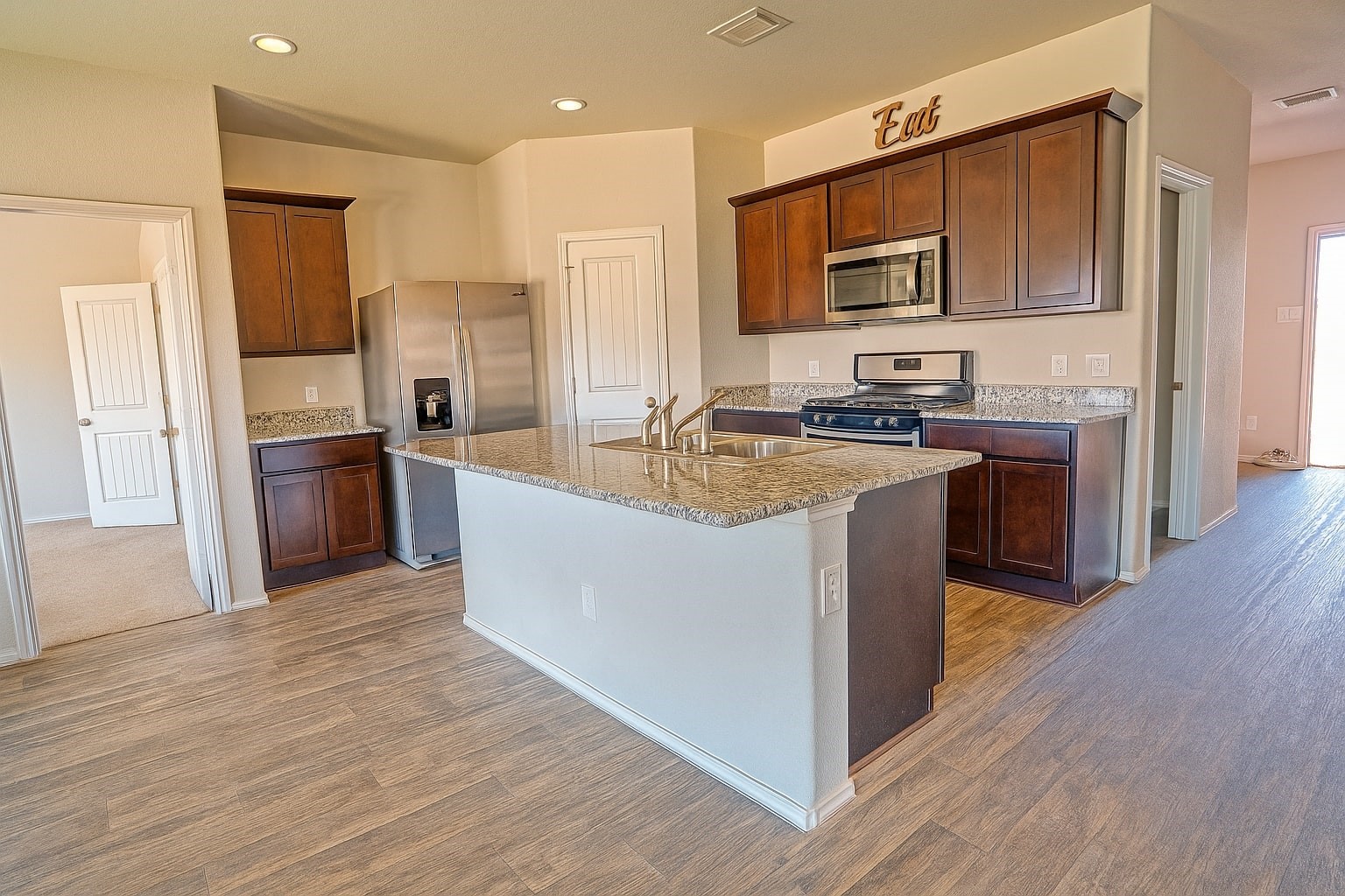 1714 Cooper Bluff Court Rosenberg, TX 77469 - Photo 4 of 21 a kitchen with stainless steel appliances granite countertop a stove top oven a sink dishwasher a refrigerator and a microwave oven with wooden floor