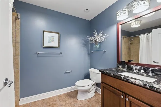 a bathroom with a granite countertop toilet a sink and a mirror