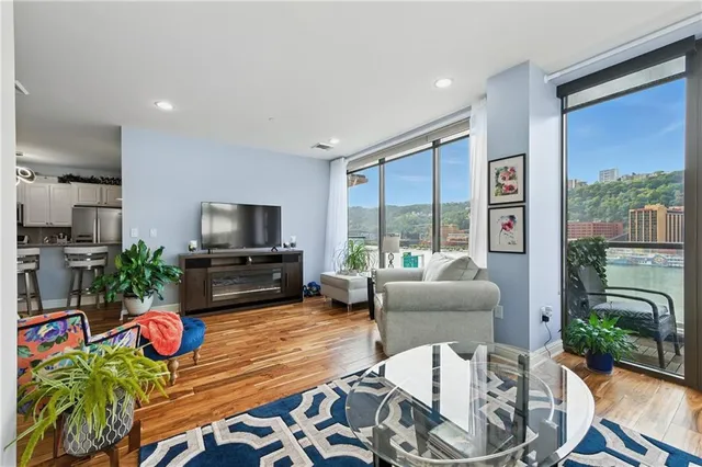 a living room with furniture a flat screen tv and a floor to ceiling window