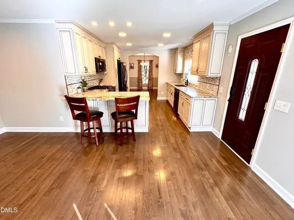 a kitchen with stainless steel appliances granite countertop sink stove top oven refrigerator and wooden floor