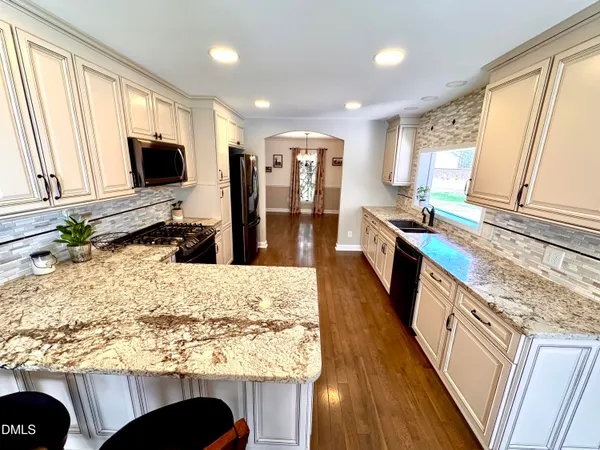 a kitchen with stainless steel appliances granite countertop a refrigerator a stove top oven a sink and dishwasher