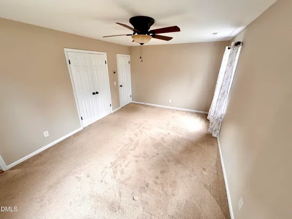 a view of a big room with windows and chandelier fan