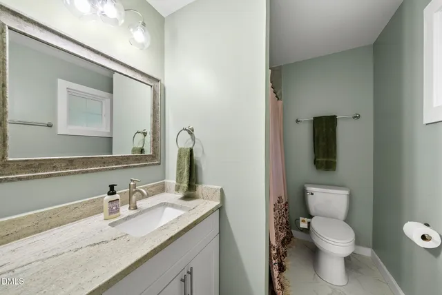 a bathroom with a granite countertop sink mirror and a toilet
