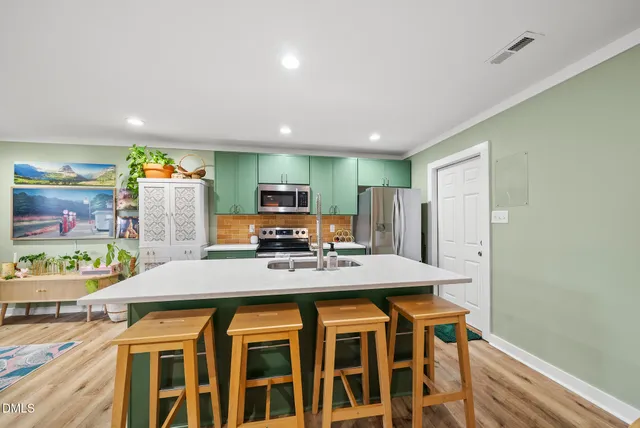 a kitchen with stainless steel appliances granite countertop a stove a refrigerator a sink a dining table and chairs with wooden floor