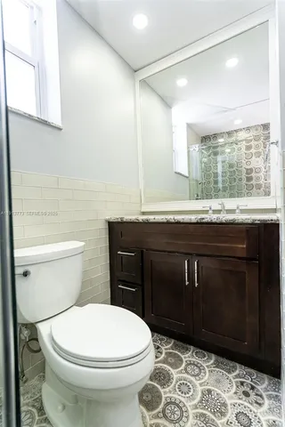 a bathroom with a granite countertop toilet sink and mirror