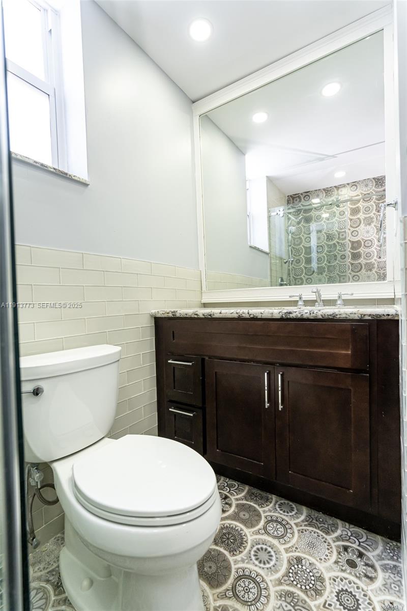 1070 West 43rd Place, Unit 38 Hialeah, FL 33012 - Photo 7 of 25 a bathroom with a granite countertop toilet sink and mirror