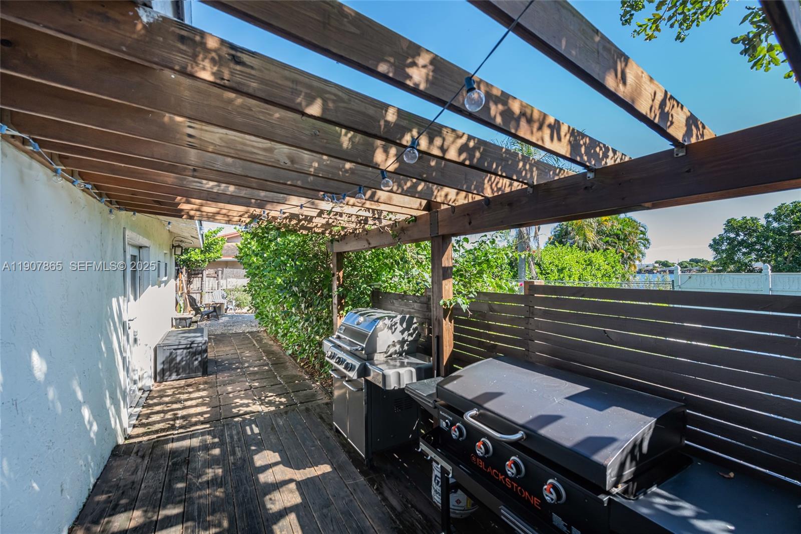 5830 North Park Road Dania Beach, FL 33312 - Photo 26 of 31 a view of a patio with table and chairs barbeque potted plants with wooden floor and fence