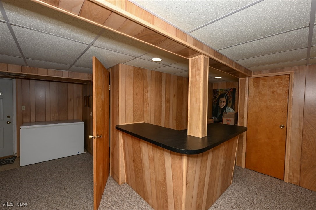 3305 Edington Road Akron, OH 44333 - Photo 38 of 46 Bar with a bar, carpet flooring, a paneled ceiling, and wood walls