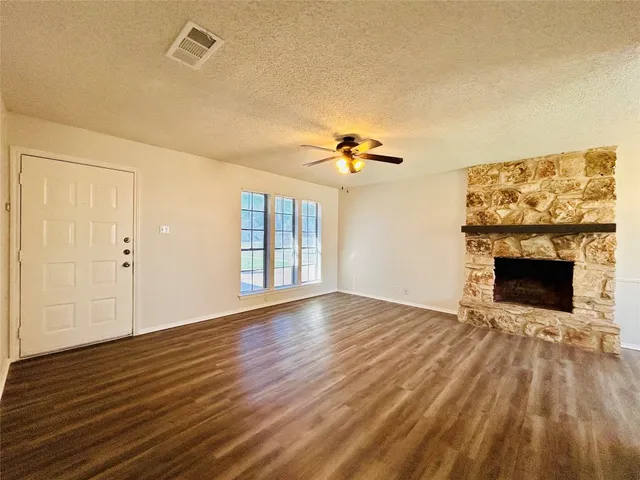 a view of an empty room with wooden floor fireplace and a window