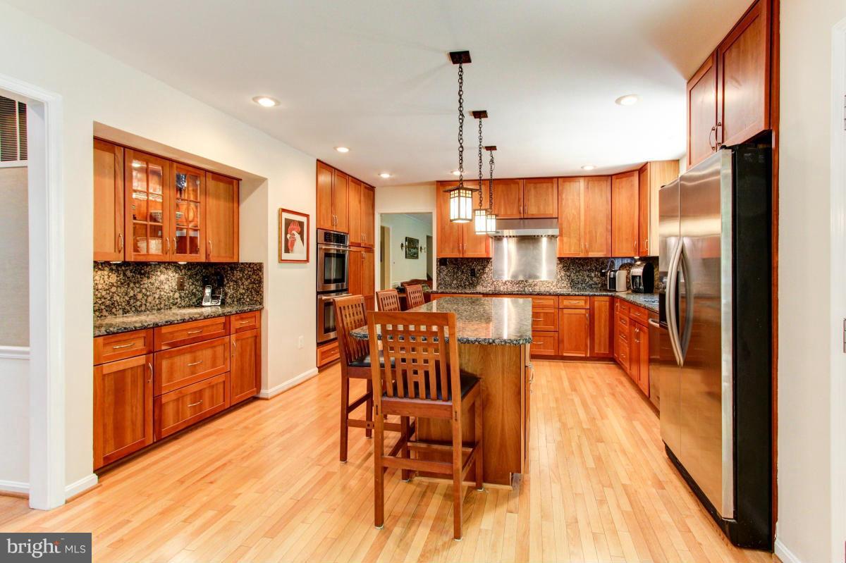 1944 Barton Hill Road Reston, VA 20191 - Photo 8 of 30 a kitchen with stainless steel appliances kitchen island granite countertop a stove a refrigerator a dining table and chairs with wooden floor
