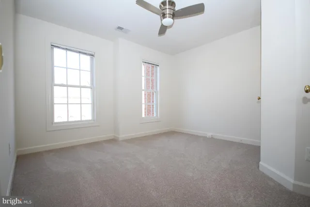 an empty room with a window and a fan