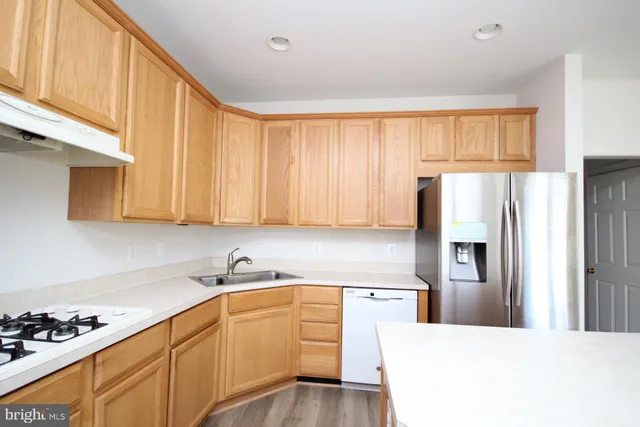 a kitchen with kitchen island granite countertop a refrigerator sink and cabinets