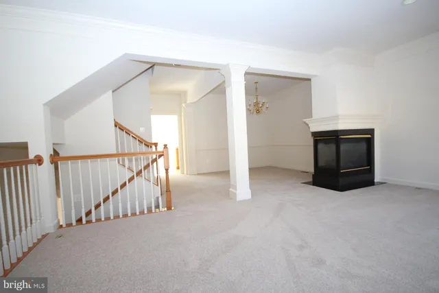 a view of an empty room with stairs and a chandelier fan