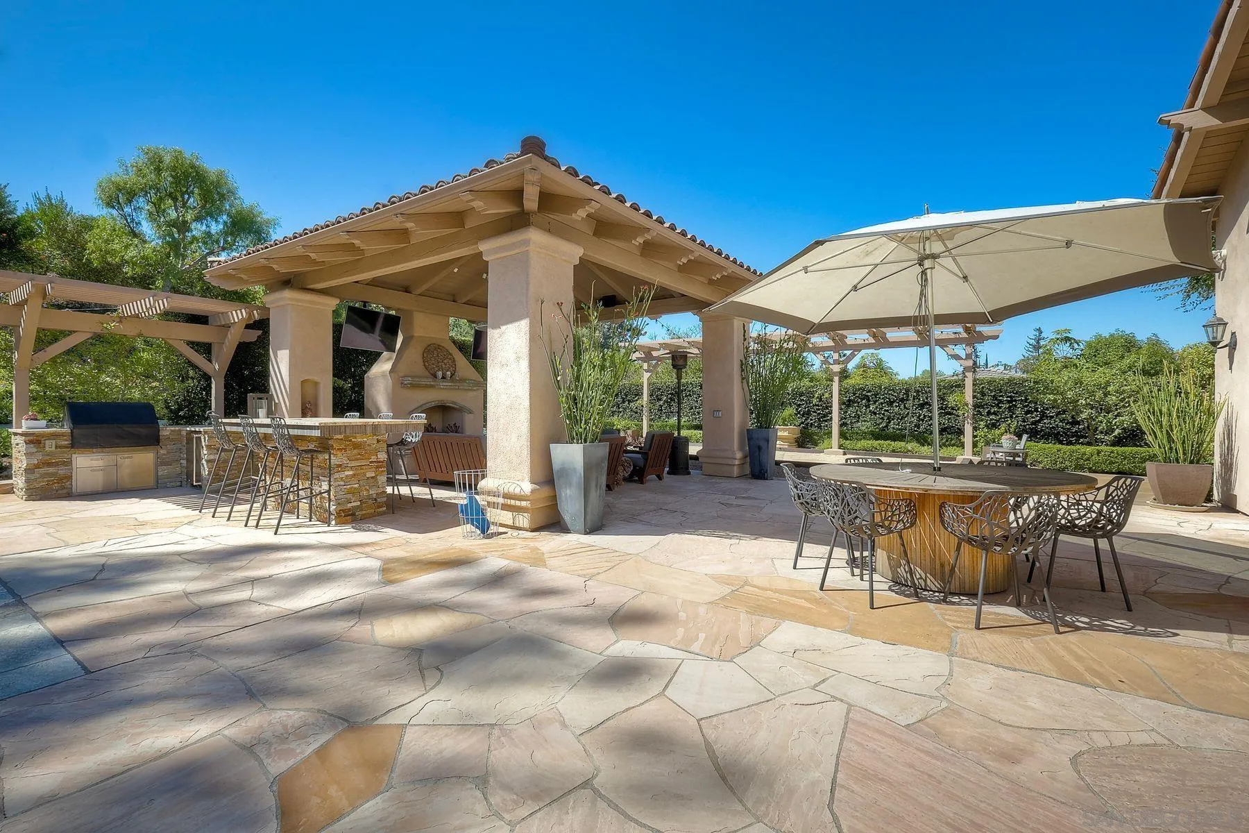 17732 Vineyard Lane Poway, CA 92064 - Photo 37 of 63 a view of a patio with table and chairs under an umbrella with a fire pit