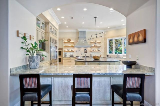 a kitchen with granite countertop kitchen island stainless steel appliances a sink and cabinets