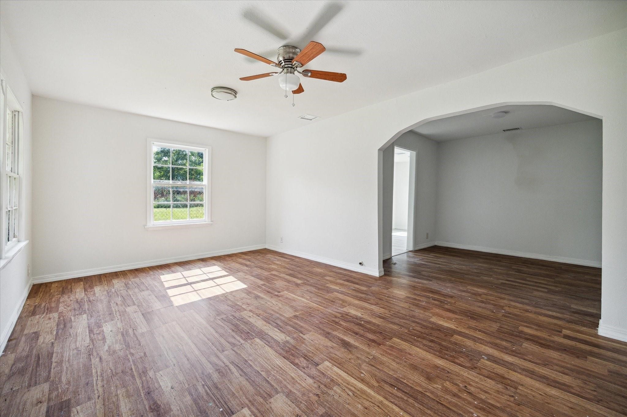 3229 Persimmon Street Houston, TX 77093 - Photo 7 of 8 an empty room with wooden floor chandelier fan and windows