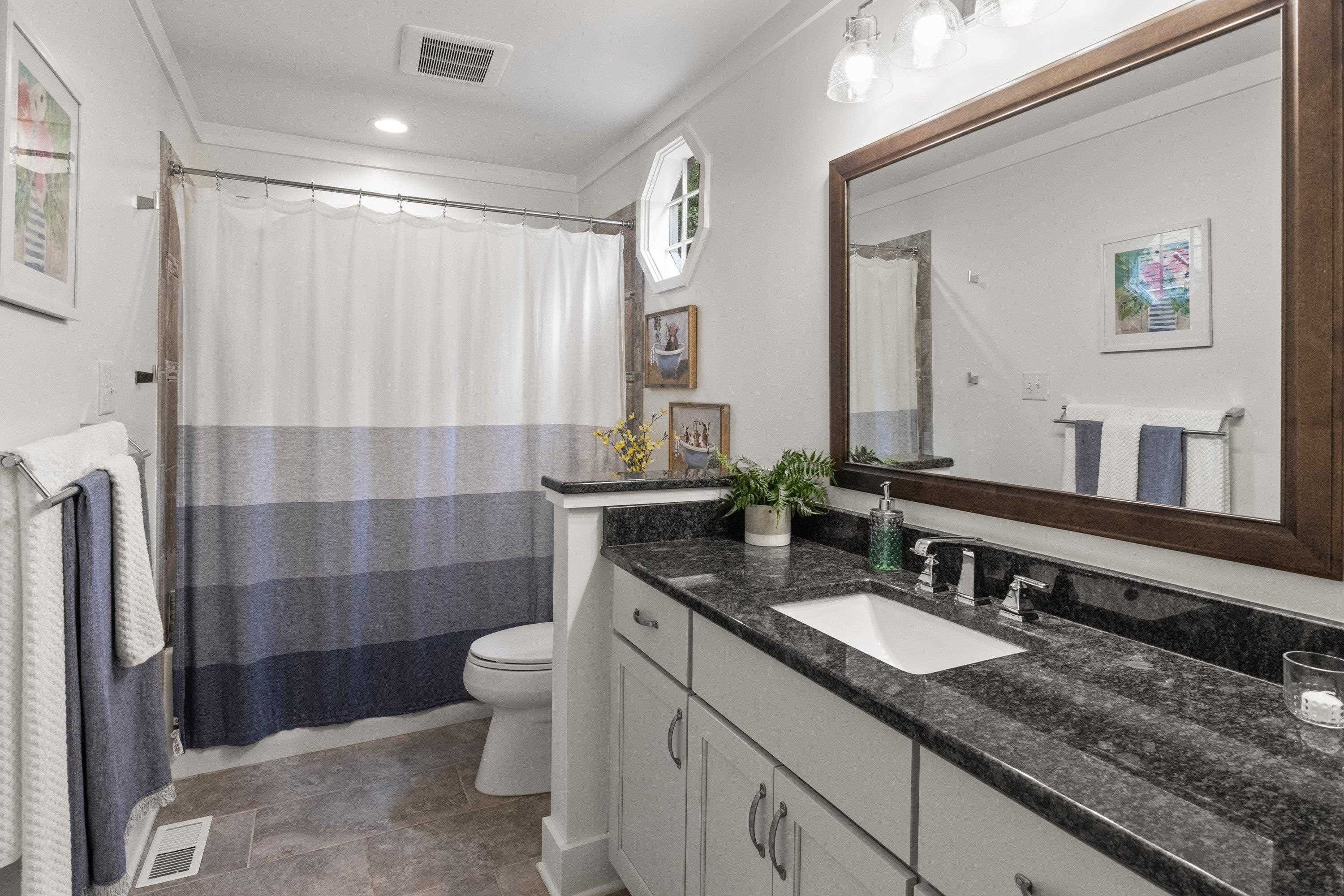 2420 Windsor Trail Raleigh, NC 27615 - Photo 40 of 72 a bathroom with a granite countertop sink a toilet a mirror a shower and a sink