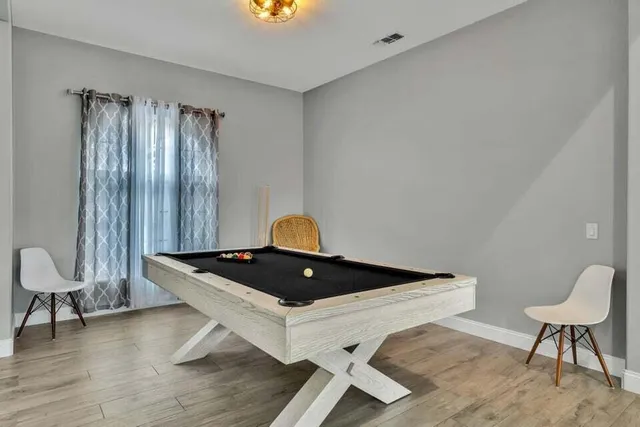 a kitchen with stainless steel appliances granite countertop a stove a refrigerator a kitchen island a dining table and chairs with wooden floor