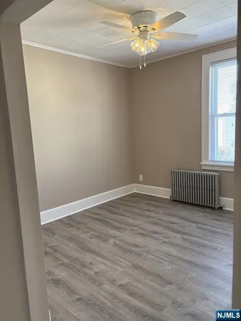 an empty room with wooden floor chandelier fan and windows