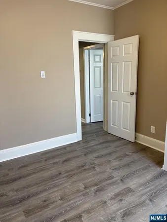 a view of an empty room with wooden floor and closet