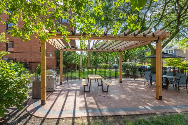 a view of a patio with table and chairs potted plants and large tree