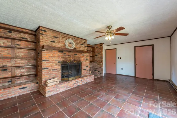 a view of a livingroom with a fireplace and a chandelier fan