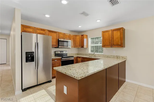 a kitchen with stainless steel appliances granite countertop a refrigerator a sink a stove a microwave and island